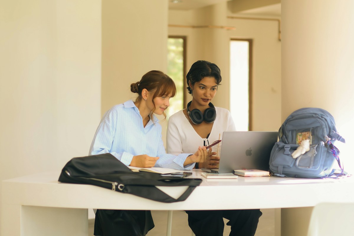 Two women studying together with a laptop and notebooks.