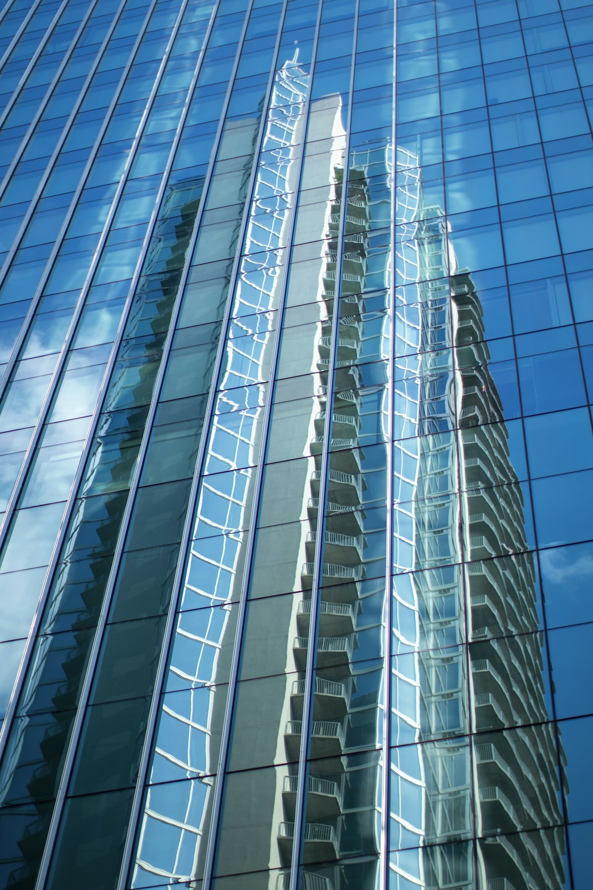 Sunlight and surrounding buildings reflected in a blue glass facade.